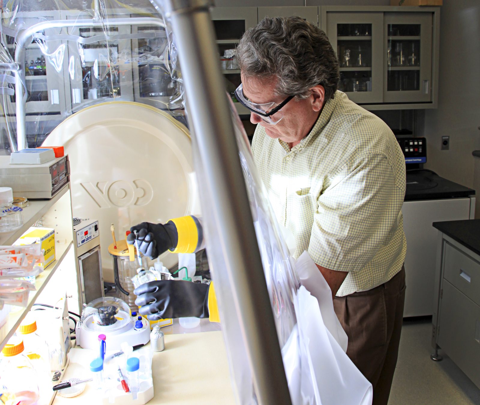 A researcher working with samples through the glove ports of a sealed anaerobic chamber used to handle oxygen sensitive microbes