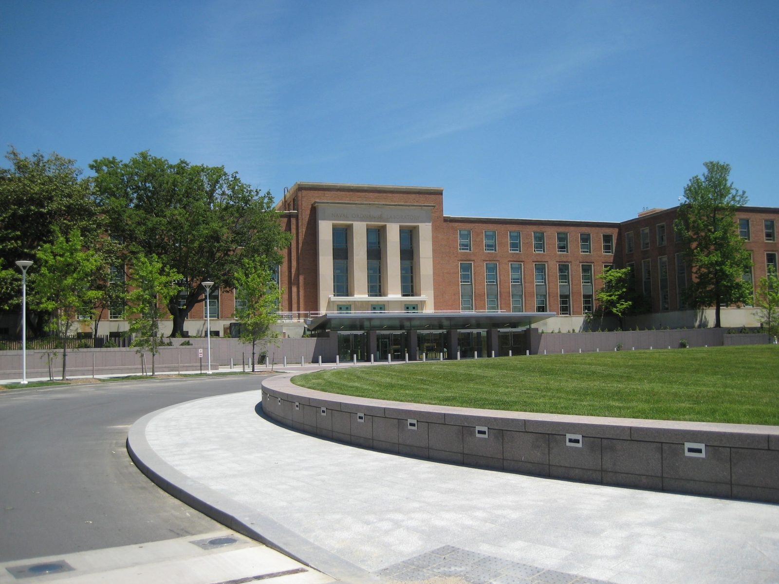 A modern brick and glass office building entrance with a circular driveway under a clear sky