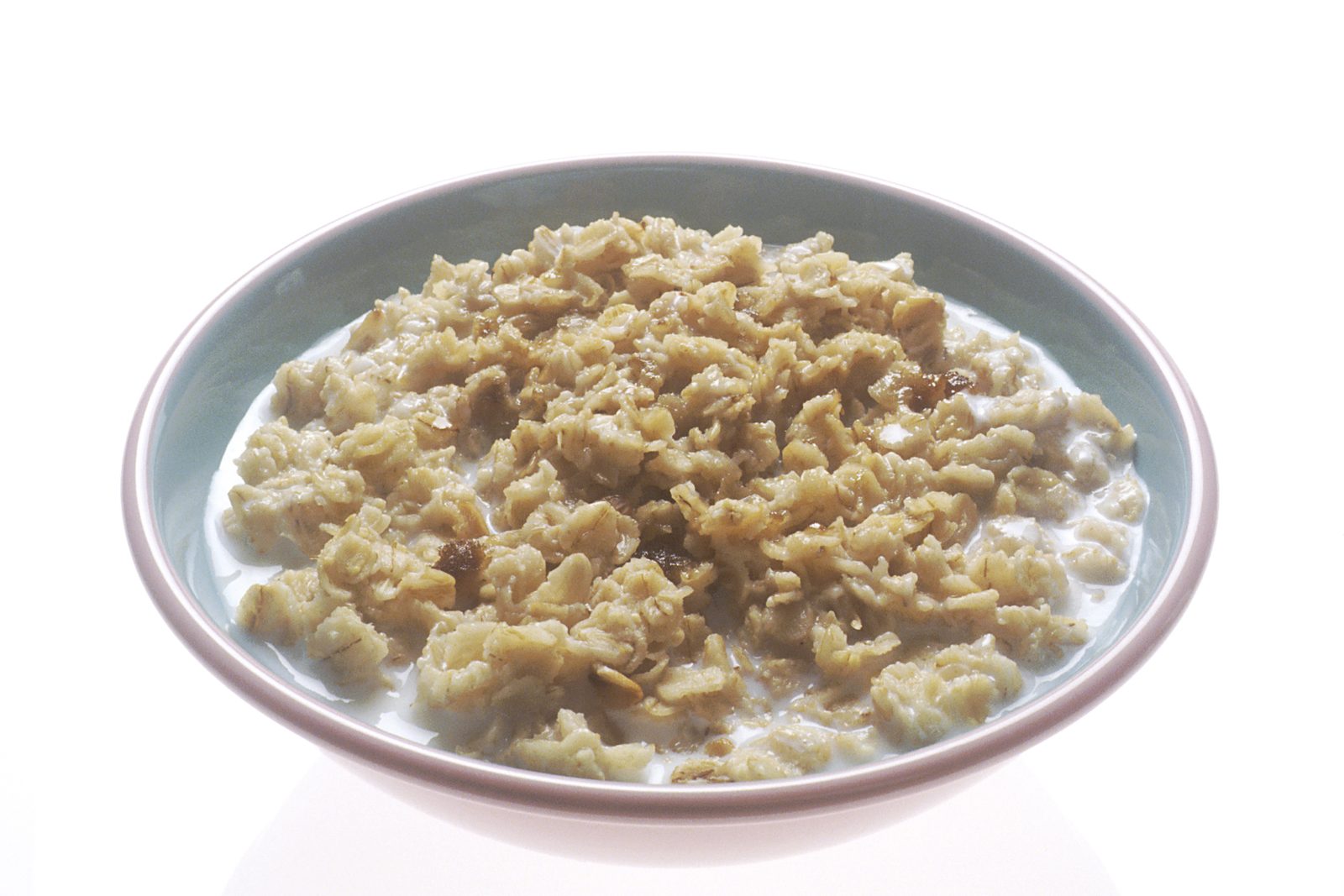 A single white bowl of cooked oatmeal with milk, photographed against a plain white background