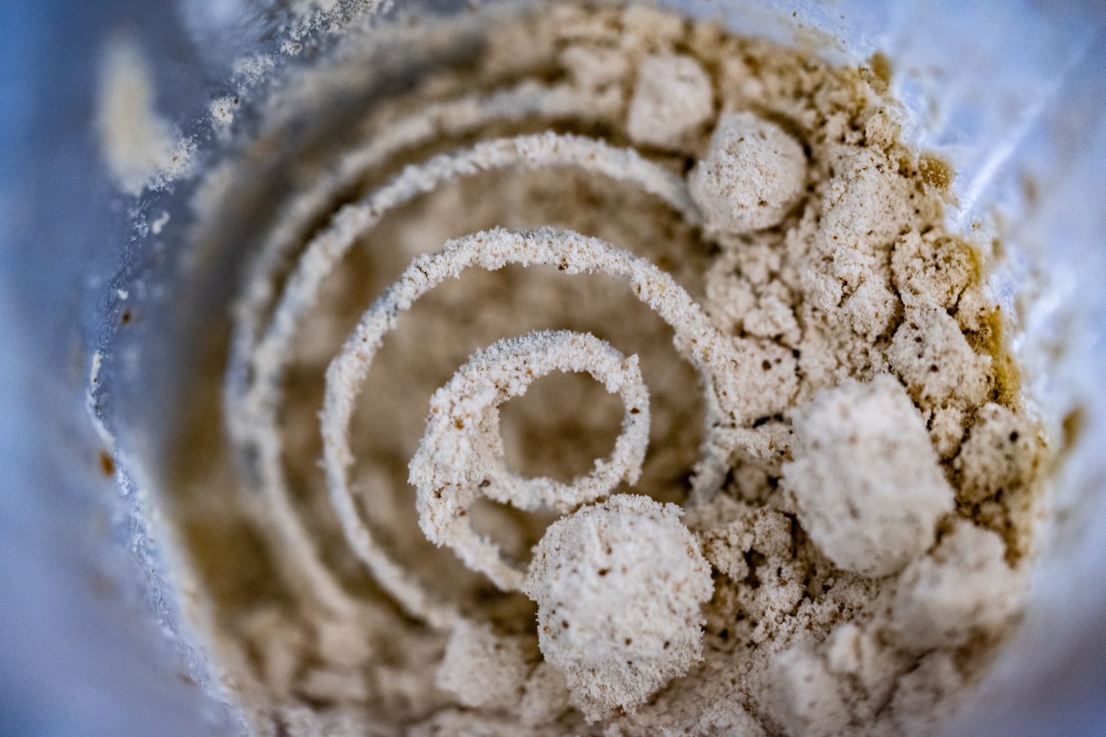A close up macro photograph of pale powder coiled in a spiral inside a shaker bottle