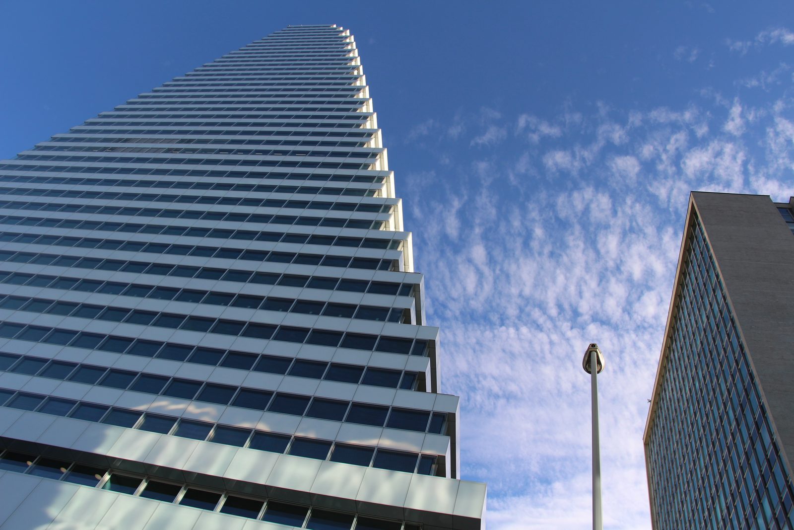 Roche's Building 1 tower in Basel, stepped glass floors rising against a blue sky with high cloud