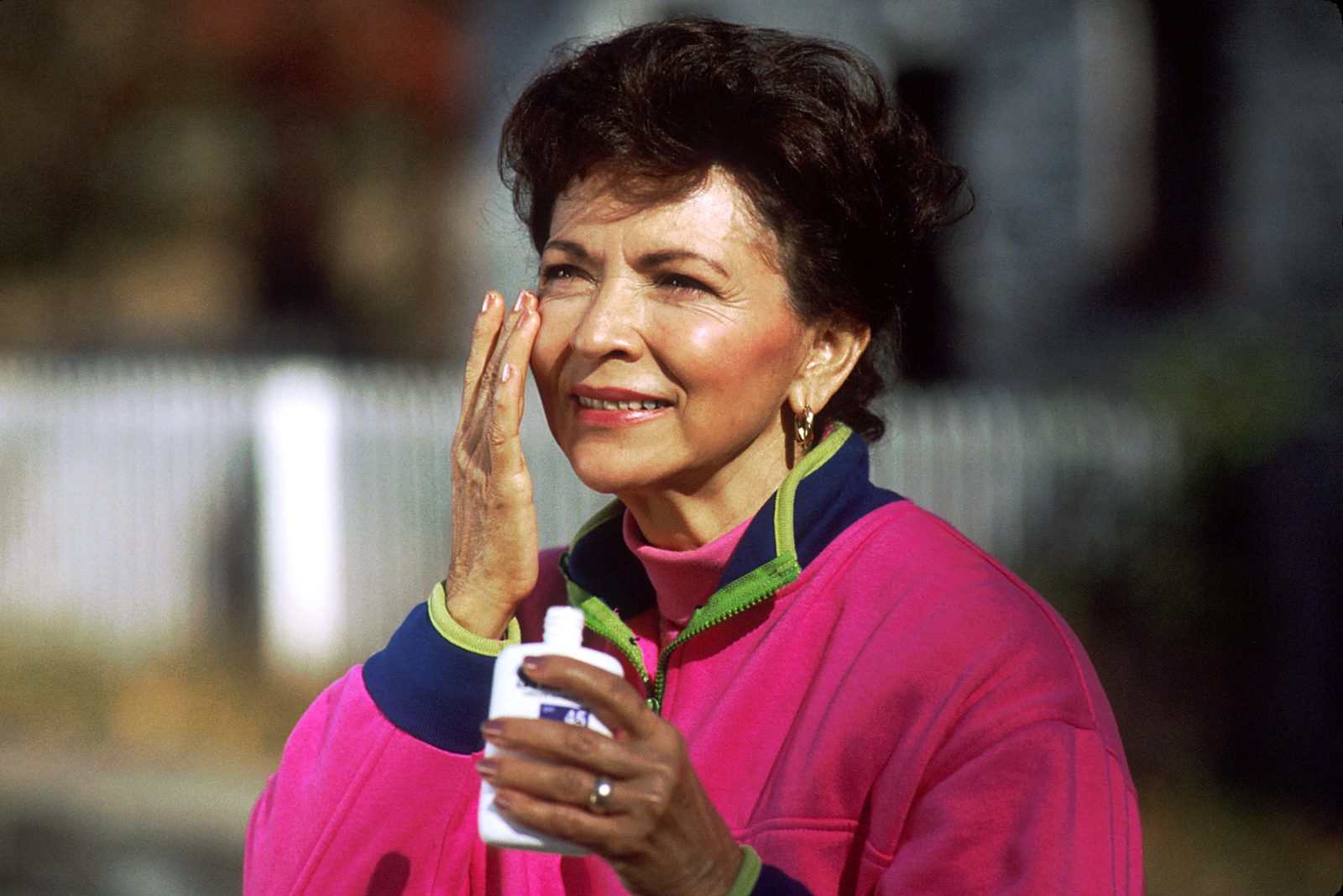 A woman applying sunscreen to her face outdoors